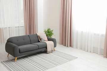 Poster - stylish living room interior with cozy sofa, houseplant and elegant curtains