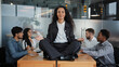 © Yuliia - Calm businesswoman leader woman doing breathing yoga exercise taking break meditating sitting at table in office in meditation background meeting business colleagues discussing project brainstorming
