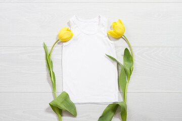 Wall Mural - White children t-shirt mockup. Template blank kids shirt top view. White wooden background. Mother women day holiday. Yellow tulip. Baby tshirt with birthday flower. Spring look.