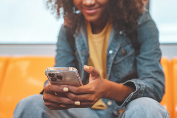 closeup - hands of african american woman passenger smile and using smart mobile phone in subway tra