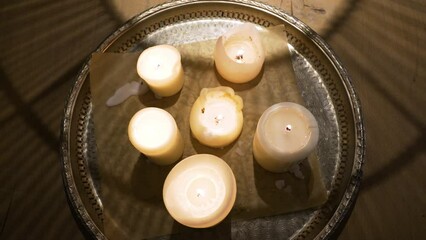 Wall Mural - Closeup shot of the lit candles on a metal tray on a wooden table