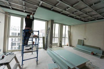 Workers assemble a suspended ceiling with drywall