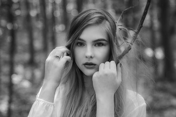 Wall Mural - Caucasian woman with blonde hairs posing in forest and looking at camera