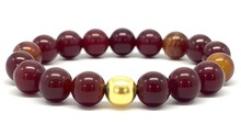  a red and gold bracelet with a gold bead on a white background with a white background and a gold bead on a red bracelet with a gold clasp.  generative ai