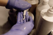 Cropped photo of woman hairdresser wearing blue rubber gloves, squeezing out shampoo mask conditioner in beauty salon.