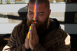 Portrait of bearded man praying, with a glare of light in the form of a rainbow on his face - a symbol of the LGBT people community