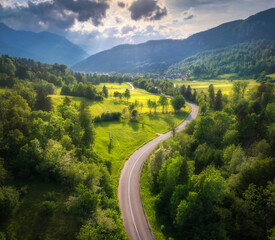 Wall Mural - aerial view of road in green meadows at summer sunny day. top view from drone of rural road, mountai