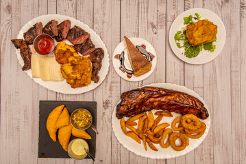 Wall Mural - A combination of Colombian gastronomy dishes with meats cooked on charcoal, corn empanadas