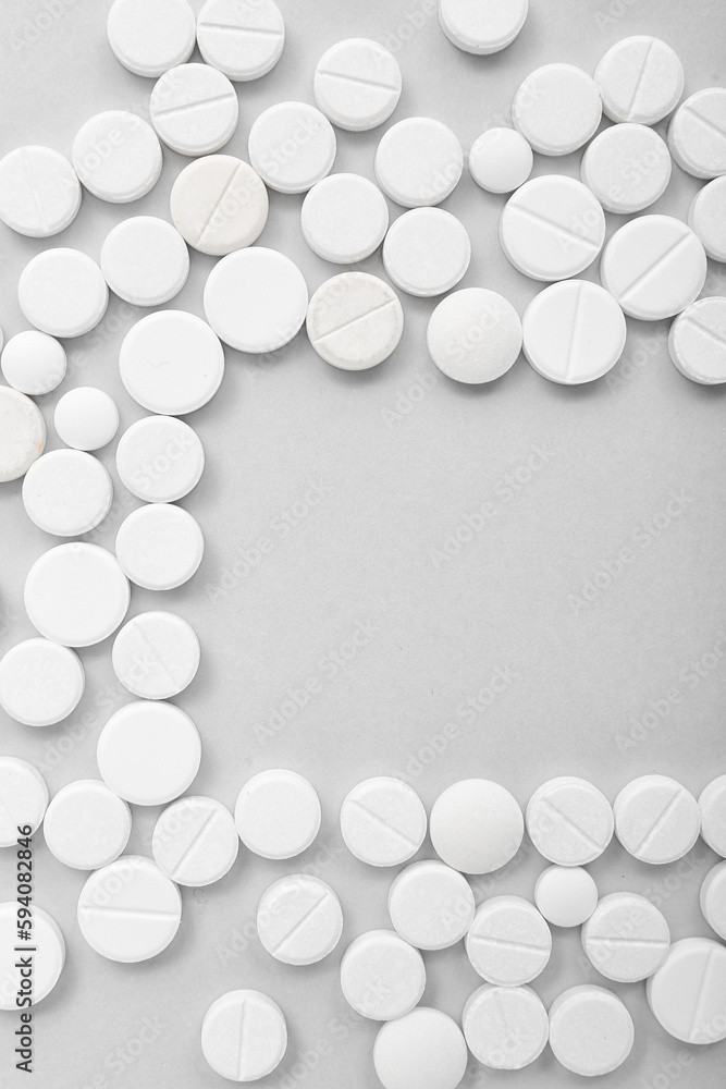 Frame made of white pills on grey background