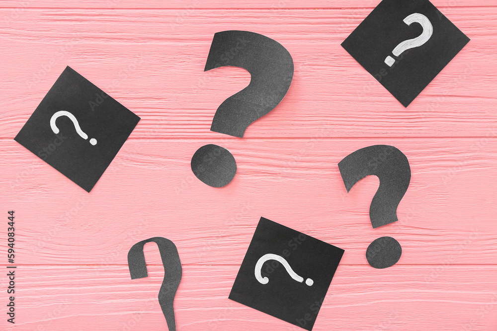 Paper question marks on pink wooden background
