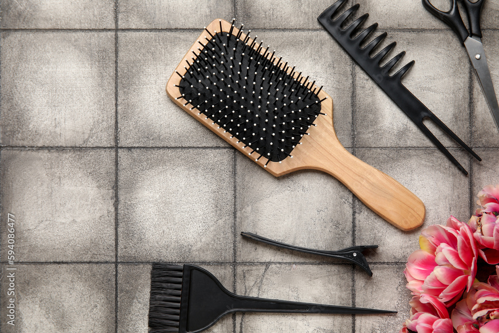 Composition with hairdresser tools and tulip flowers on grey tiled table