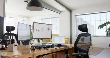 Empty modern office with graphs on computer screens and plants in pots on tables