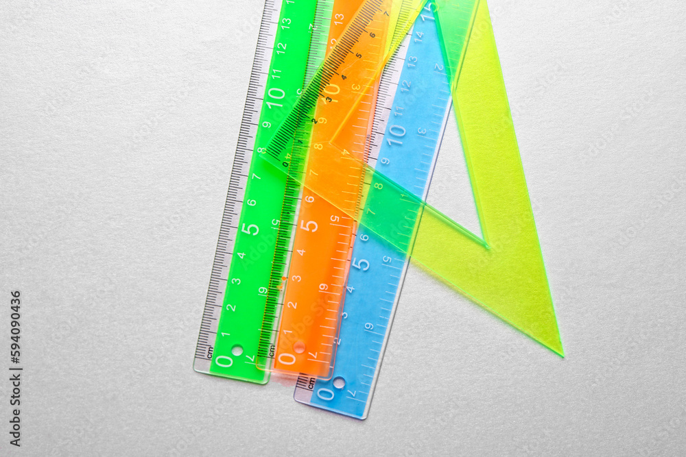 Colorful straight and triangle plastic rulers on grey background