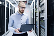 © MVProductions - IT computer specialist holding laptop in his hands and inspecting servers at datacenter. High quality generative AI