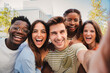 © Jose Calsina - Happy multicultural friends laughing taking a selfie portrait together. Mixed teenage cheerful students having fun and hanging out. Young multiracial joyful people looking at camera and bonding . High