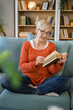 © Miljan Živković - Senior woman mature caucasian female read book at home wear eyeglasses