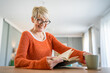 © Miljan Živković - Senior woman mature caucasian female read book at home wear eyeglasses