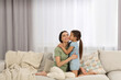 © New Africa - Happy woman and her cute daughter spending time together on sofa at home. Mother's day celebration