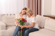 © New Africa - Young daughter congratulating her mom with flowers at home. Happy Mother's Day
