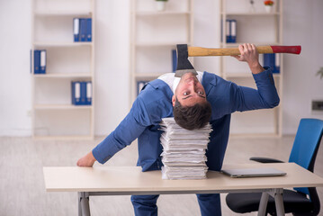 Wall Mural - Young male employee unhappy with excessive work in the office