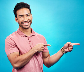 Wall Mural - Point, mockup and portrait of Asian man on blue background for news, information and announcement. Advertising, studio mockup and male pointing for branding copy space, promotion and show gesture