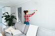 © okrasiuk - Young woman in plaid shirt doing measuring with a measure tape on the wall. Girl wants to put a picture on the wall at home. Housekeeping work. Doing repair herself. DIY, equality in work concept.