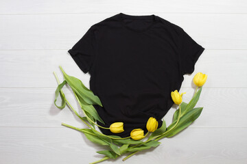 Wall Mural - Black t-shirt mockup. Template blank shirt top view. White wooden background. Mother women day holiday. Yellow tulips. Woman tshirt with birthday bouquet flowers. Spring look. Female accessories