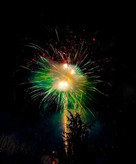 Sticker - Vertical shot of green orange red fireworks in a foggy night sky. Italy