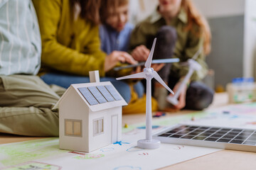 Canvas Print - Close-up of house model with solar system and wind turbine during a school lesson.