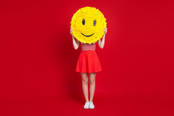 Wall Mural - Full length portrait of sporty slender person hands hold big smiley emoji collage cover face isolated on red color background