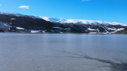 Sticker - Raising drone shot over the sea near snowy mountains in Voss, Norway with blue sky