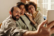 Happy family making selfie portrait on smartphone with African American adopted girl in the room at home