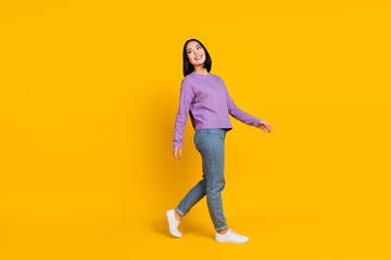 Wall Mural - Full length photo of pretty dreamy woman wear violet shirt walking looking back empty space isolated yellow color background