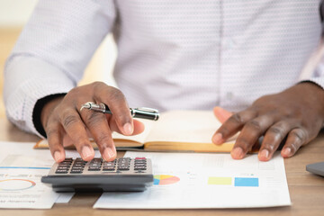 Wall Mural - African black businessman sitting doing a financial report and studying annual profit analysis An accountant checking the financial status of the company is in the office.