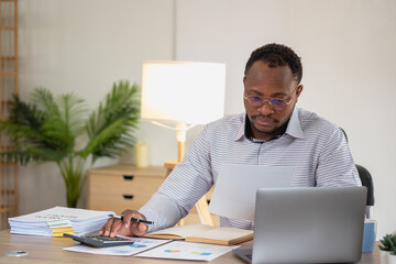 Wall Mural - African black businessman sitting doing a financial report and studying annual profit analysis An accountant checking the financial status of the company is in the office.