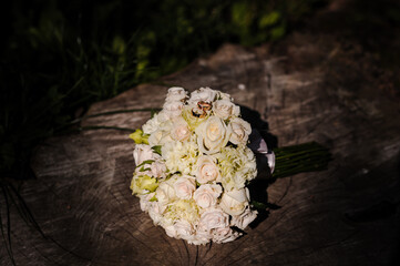 Wall Mural - Two golden wedding rings on a stump, a bride's bouquet of flowers in the background