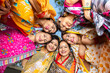 © GAJENDRRA BHATI  - Group of happy young traditional indian women wearing colorful sari looking down and embracing each other like a team. Rural india. women empowerment.