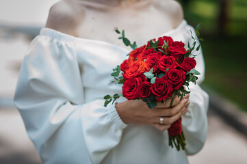 Wall Mural - Bouquet of red roses in the hands of the bride. Bridal bouquet in woman's hands