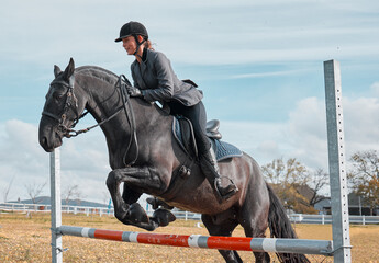 Canvas Print - Galloping away on a new adventure. a young rider jumping over a hurdle on her horse.