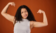 Im crazy strong. Cropped portrait of an attractive young woman flexing her biceps in studio against a red background.