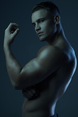 Sticker - The picture of strength and masculinity. Studio portrait of a muscular young man posing shirtless against a dark background.