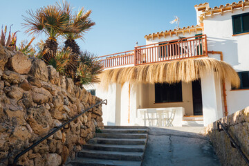 une maison des Baléares. Une maison en Espagne. Un toit de paille dans un pays chaud. Terrasse ombragé en été. Chaleur estivale sous les tropiques. Vacances. Une entrée de maison dans le sud. Majorque