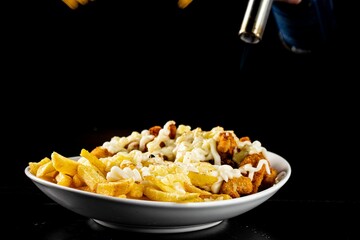 Sticker - Bowl of tasty meal with french fries, chicken nuggets and a sauce on a black background