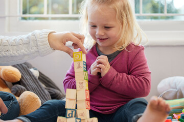 Wall Mural - Lets add one more. a little girl stacking blocks with her mother at home.