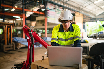 Wall Mural - Professional engineer holding robot controller checking and repairing automatic robotic machine at industrial factory, Technician worker working with robotic arm system for manufacturing production