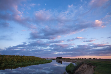 Canvas Print - Beautiful colors of cloudy sky above the river in dusk on warm summer evening. Calm and beautiful evening landscape