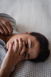 © LIGHTFIELD STUDIOS - Young multiracial woman with psychological problem lying on bed at home.