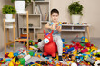 © Zarina Lukash - A little boy is jumping on an inflatable rubber donkey among the mess in the children's room. Bouncing toy for kids.