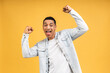 Cheerful handsome African american man making yes gesture while excited about winning. Ecstatic young fan rooting and expressing support. Success concept isolated over yellow background.