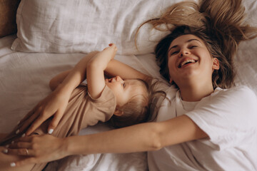 Wall Mural - small child plays with mother in bed